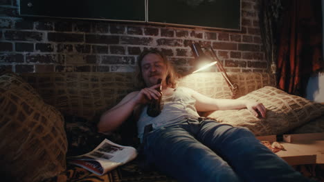 man relaxing on a couch with beer and pizza