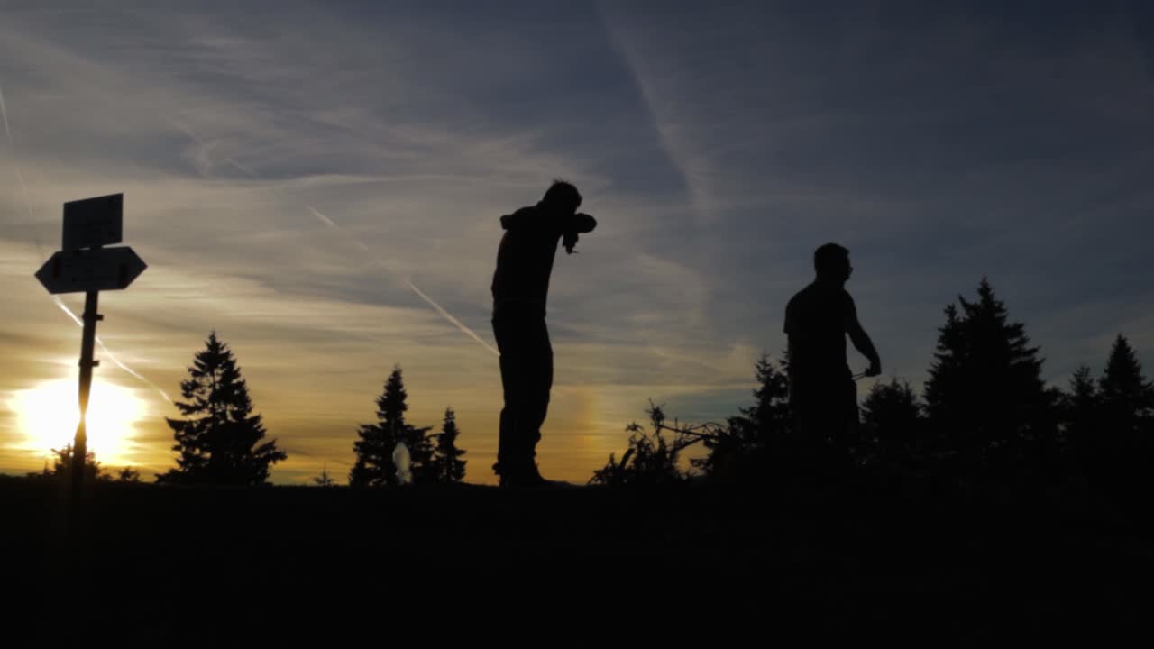 panoramización de derecha a izquierda en una vista épica de la puesta de sol en las montañas con dos excursionistas y algunos pinos en las sombras en el parque nacional buila-vanturarita, parte de las montañas de los cárpatos