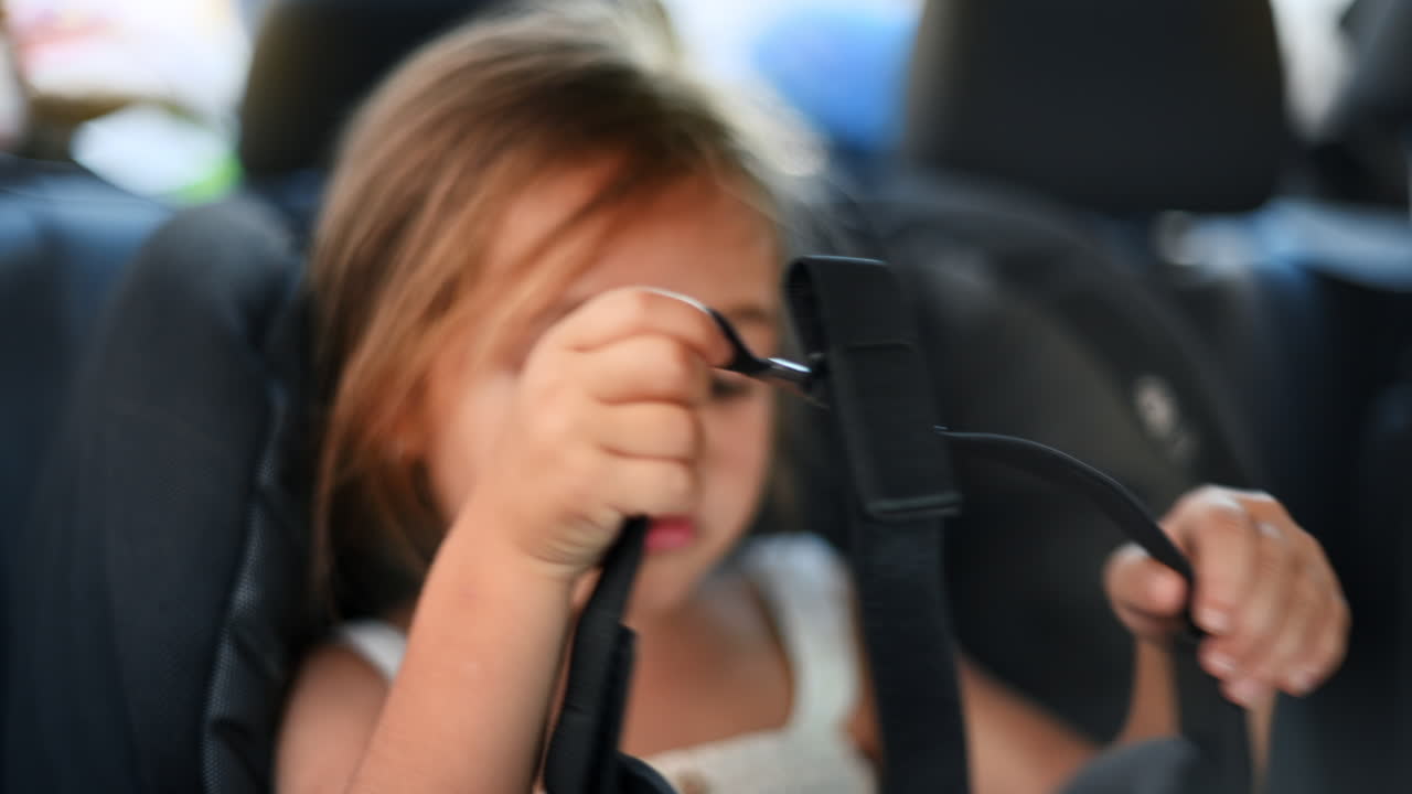 Niña pequeña sentada en el coche poniéndose gafas de realidad virtual en una silla de seguridad infantil