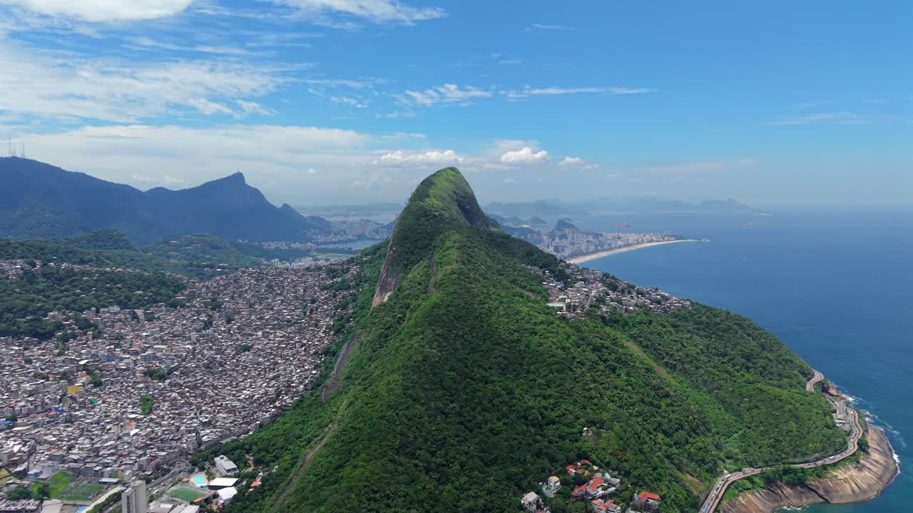 Vetta verde lussureggiante che si erge sopra Rocinha e la costa di Rio, dividendo le dense abitazioni urbane dalla fitta foresta verde e dall'oceano, tracking aereo verso destra