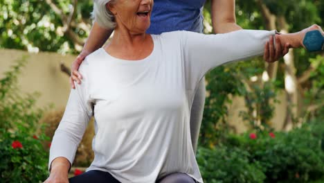 Female-trainer-assisting-senior-woman-in-exercising-with-dumbbells-4k