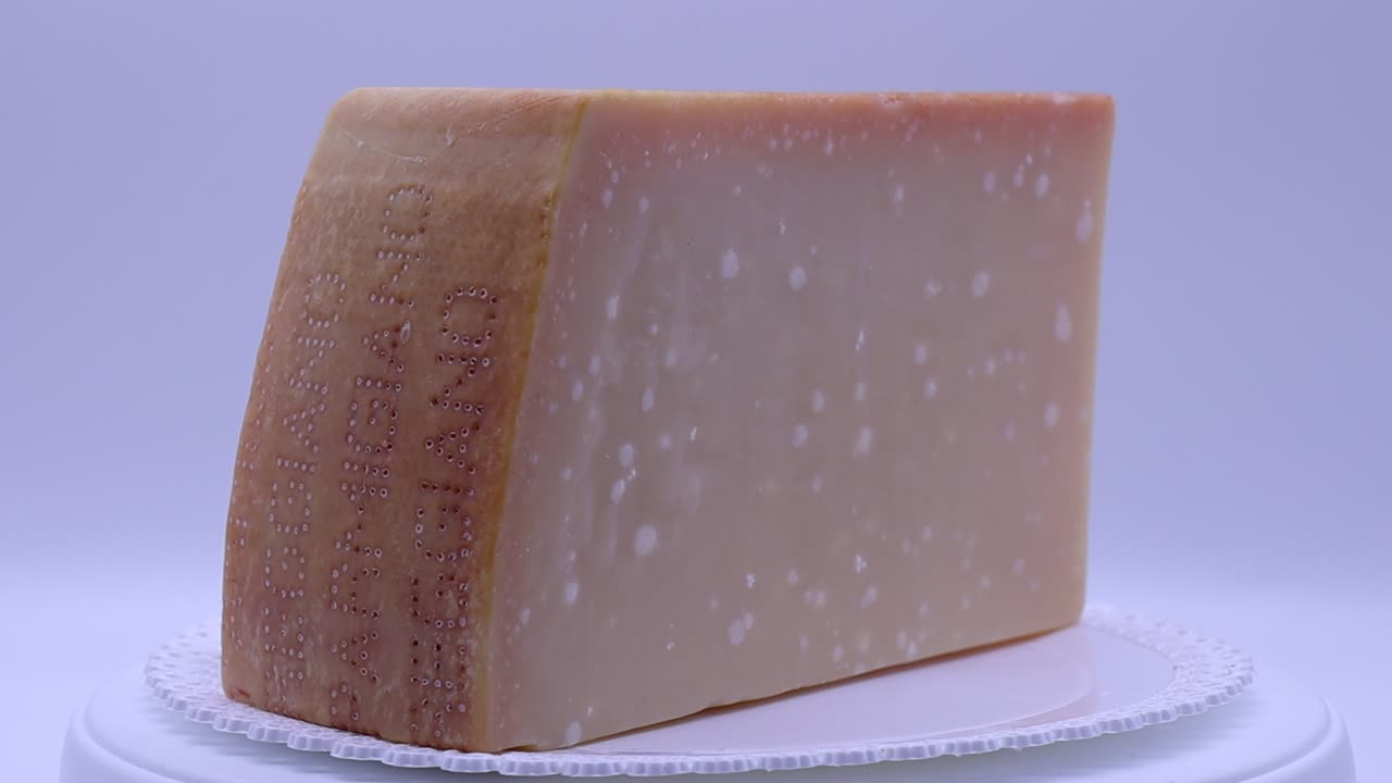 Italian Parmigiano Reggiano cheese with cheese knife rotating on turntable