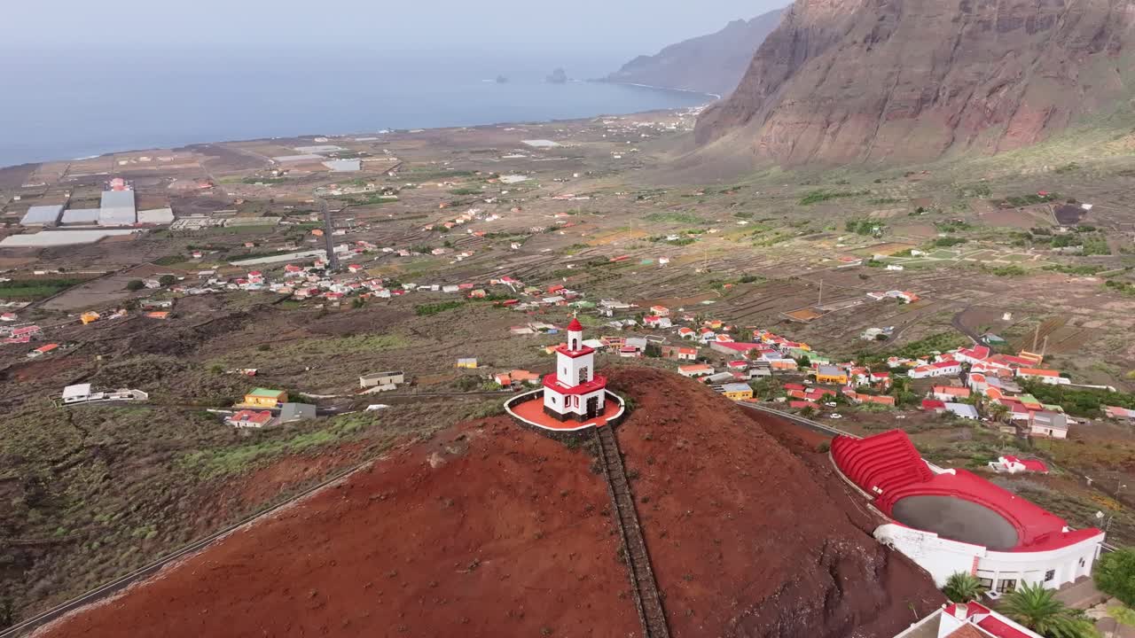 Red and white bell tower of Joapira overlooks green valley, distant Las Puntas