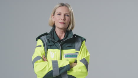 Full-Length-Studio-Portrait-Of-Serious-Mature-Female-Paramedic-Against-Plain-Background