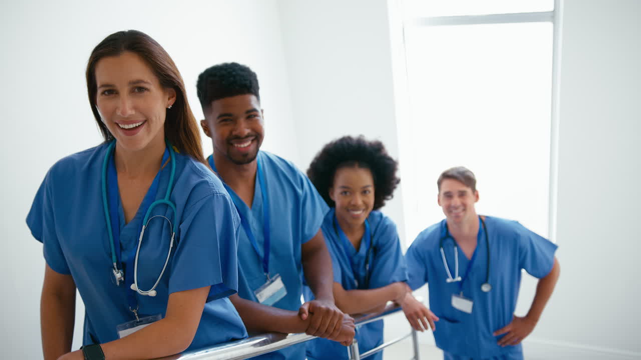 Ritratto di team medico multiculturale sorridente in camice, in piedi sulle scale in ospedale