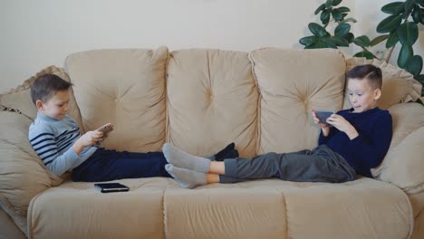preschool boys holds modern mobile phone and plays cheerfully video game. focus on smartphone.