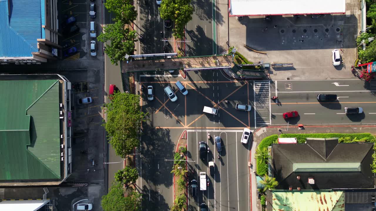 Timelapse of bustling traffic along a three-way junction in Ortigas Avenue, San Juan City, Philippines - aerial top-down