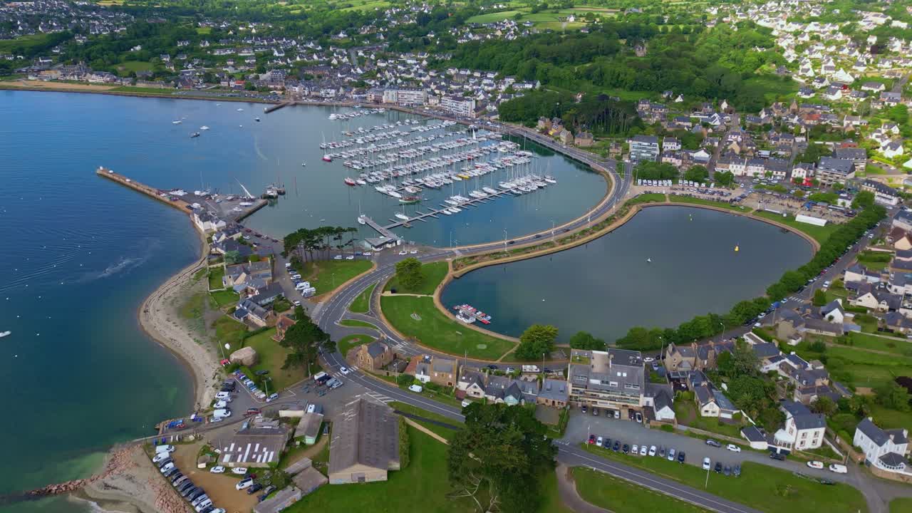 Drone flies toward Perros-Guirec port and city, tilting down mid-flight to reveal the peninsula and surroundings