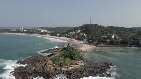 Aerial-orbits-rocky-point-on-SW-ocean-coast-of-Hikkaduwa,-Sri-Lanka