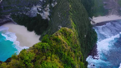 waves rolling onto perfect beaches on both sides of a rugged, green escarpment