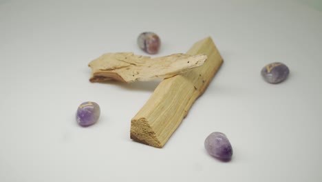 morceaux de bois de palo santo et de pierres précieuses gravées de symboles dorés sur fond blanc, pur - gros plan