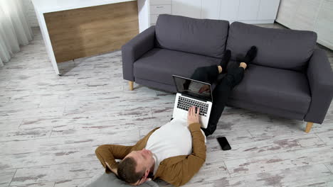 man lying in living room. young man using laptop while lying on floor at home