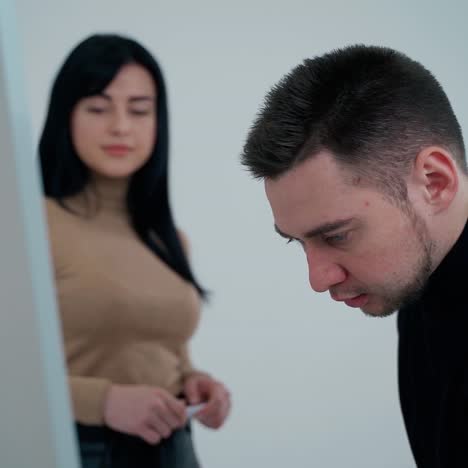 man and woman near the board indoors. young man writing on a white board with a marker. business workers think about new project.