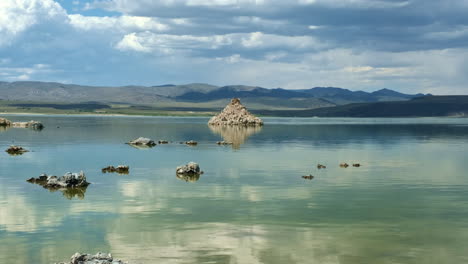 Amplia-Toma-De-Paisaje-Del-Cristalino-Y-Suave-Lago-Mono-De-California,-Con-Tobas-De-Piedra-Caliza-Con-Reflejos-De-Nubes-Y-Montañas-En-El-Fondo