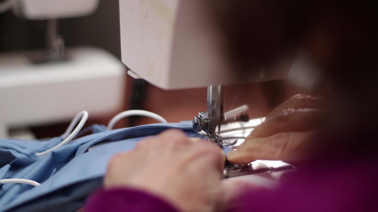 Seamstress making protective surgical mask against covid-19 coronavirus using sewing machine handmade protective gear production