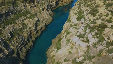 Arial-shot-of-Wied-Il-Ghasri,-a-secluded-inlet-with-a-tiny-pebbly-beach-wedged-between-high-cliffs-on-the-island-of-Gozo-in-Malta