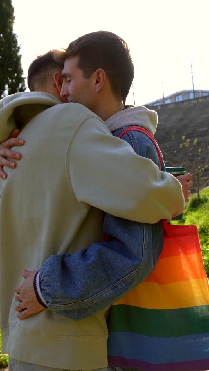 A couple shares a warm embrace with a rainbow flag