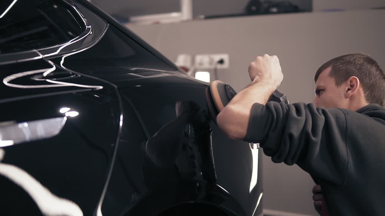 검은 차를 문지르며 완벽한 시선을 얻기 위해  ⁇ 화 기계로. 젊은 남성 오토센터 대표.