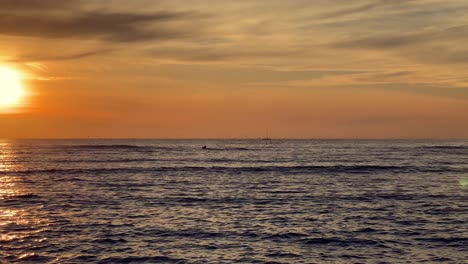 clip del sol en el agua con olas, mar, océano, río, lago o laguna con viento y el reflejo de los colores del atardecer.