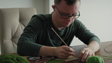 close up of adult caucasian man with down syndrome making a craft at home