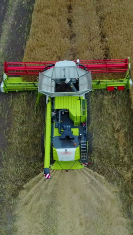 combine harvester working on a field. aerial view of combine harvester on farm field vertical video