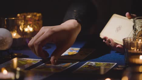 Cerca-De-Una-Mujer-Dando-Lectura-De-Cartas-Del-Tarot-En-Una-Mesa-A-La-Luz-De-Las-Velas-Sosteniendo-La-Carta-De-Los-Amantes-2