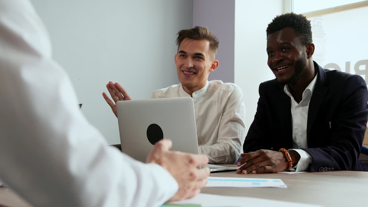 Modern office workers sitting at a laptop solve creative tasks to create new business products. Multi-ethnic groups of men and women
