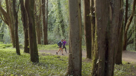 male and female runners running uphill in forest