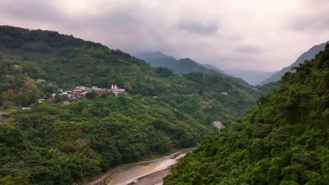 Aerial-approaching-shot-of-green-mountains-in-wulai-烏來-traffic-on-road-during-cloudy-day