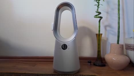 bladeless fan on the floor, in a home, turning from side to side blowing wind