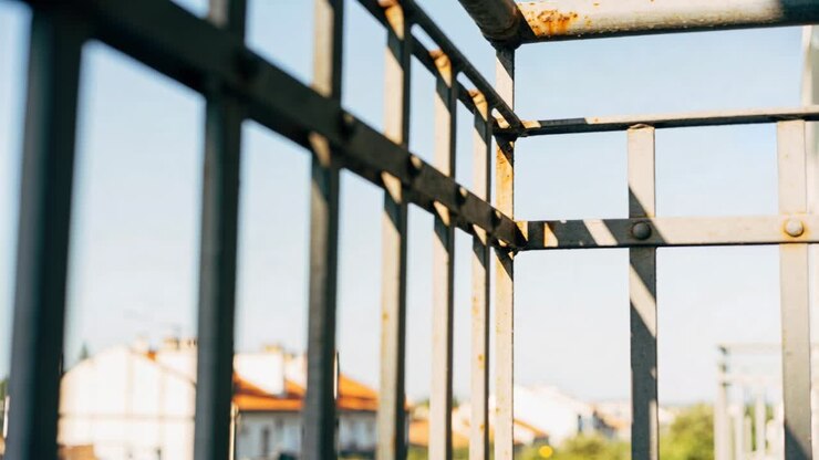Shifting camera lens revealing painted metal railing at rooftop balcony, showing rust and bolts