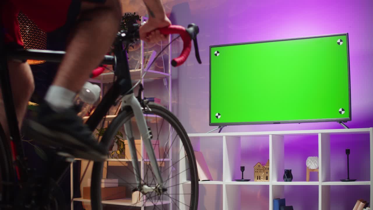 녹색 스크린 tv와 함께 집에서 자전거를 타는 남자