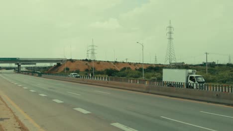 Toma-Aérea-Al-Lado-De-La-Autopista-De-Karachi-Con-Pilones-En-Segundo-Plano