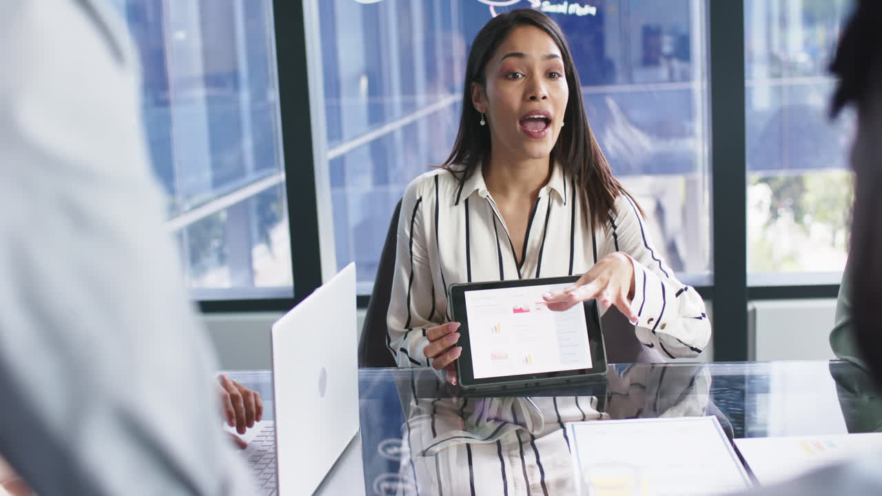 Presenting data on tablet, businesswoman leading meeting with colleagues in office