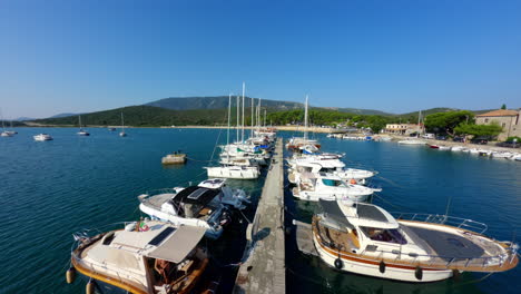 cinematic fpv drone soars along empty dock with sailboats and yachts at pier of osor island croatia