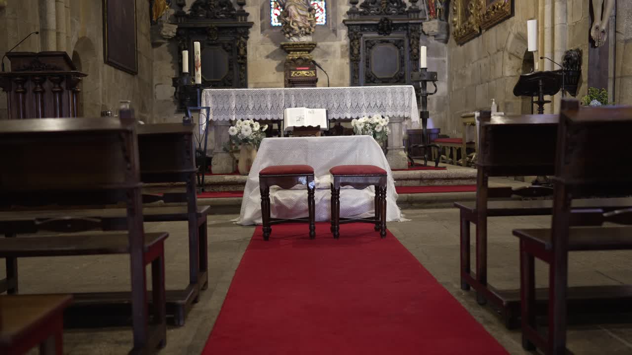 Altare ornato con tappeto rosso e due sedie preparato per un matrimonio in chiesa