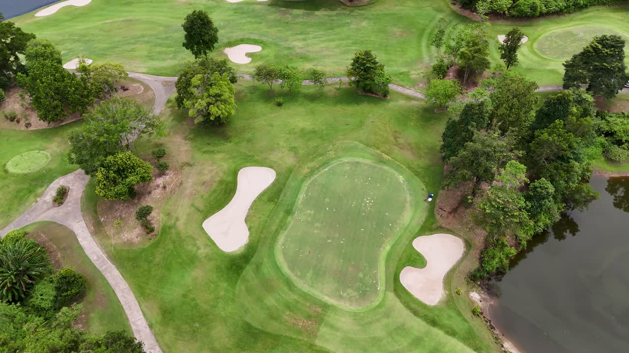 Aerial footage showcases a lush golf course in Phuket, Thailand, highlighting greens, bunkers, and surrounding nature under soft daylight