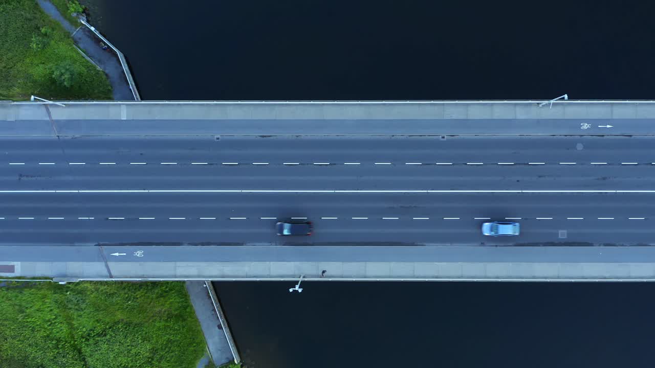 автомобили пересекают мост, пересекающий спокойную воду реки.