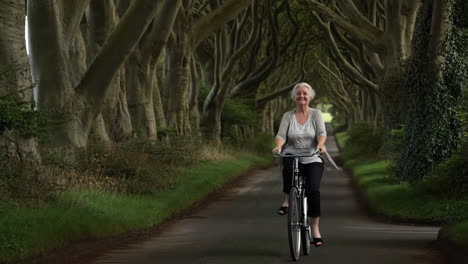 a woman cycling along the iconic dark hedges avenue