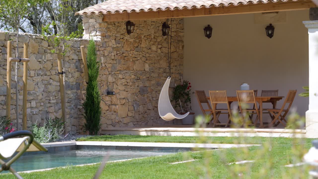Slow revealing shot of a swimming pool with garden furniture surrounding