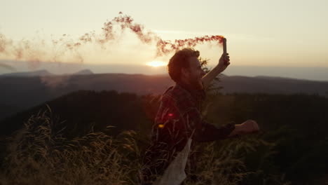 male hiker running in field with smoke bomb