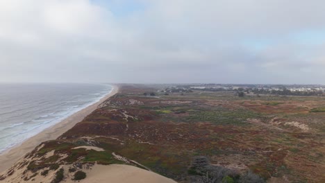 an overhead perspective blends natural dunes with a distant view of highway 1 tracing the california coast.