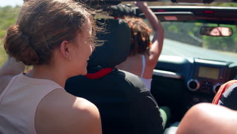 un grupo de amigas en un coche de techo abierto en un viaje por carretera se dan unos a otros los cinco