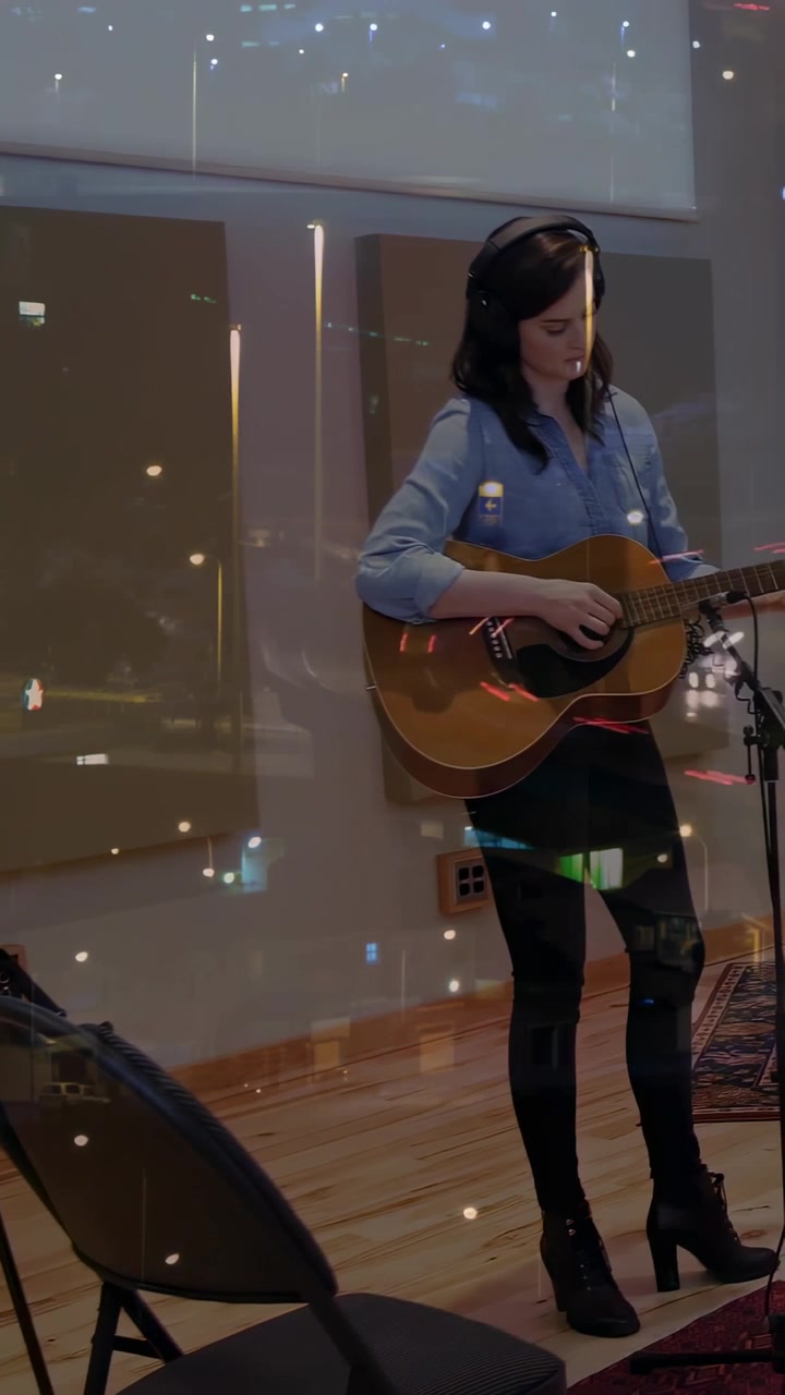 Video vertikal: Menyetel gitar, wanita berkaos biru dengan headset dan memetik di mikrofon studio untuk rekaman