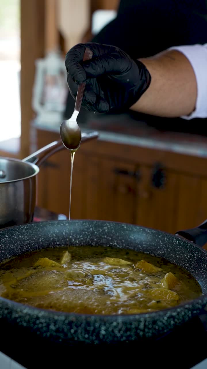 Watch as a skilled chef intricately pours golden syrup into a bubbling pot, crafting a delicious treat. The aromatic blend of spices and rich flavors fills the air, creating a sensory delight