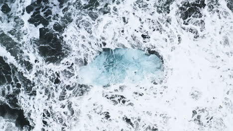 stunning drone shot of waves breaking on a beautiful ice rock at diamond beach in iceland