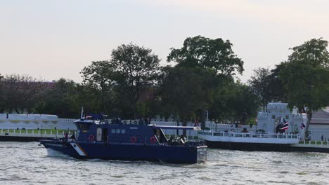 a tugboat moves along the river by a park