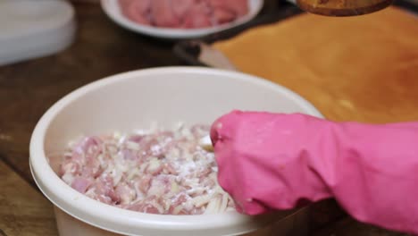 adding spoonfuls of salt to a bowl of raw chicken for shashlik and shish kebab