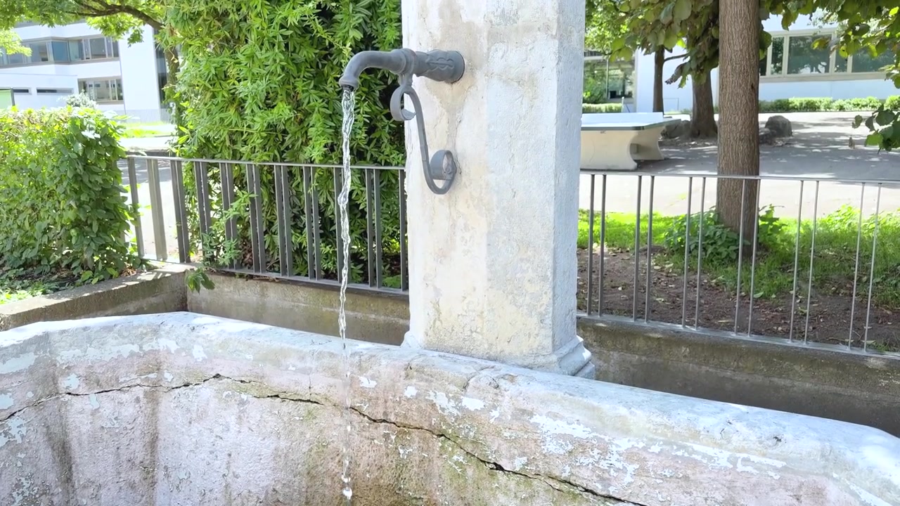 Una fontana in cemento invecchiato a Lörrach, Germania, si riempie gradualmente di acqua fresca che scorre nella vasca. Muri coperti di muschio. Ripresa dall'alto con movimento tilt up.
