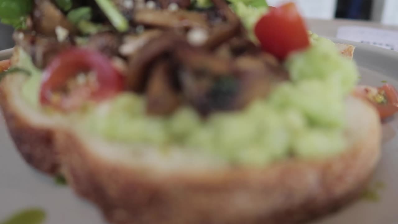tostada saludable de aguacate a base de plantas veganas con champiñones, tomates cherry y rúcula